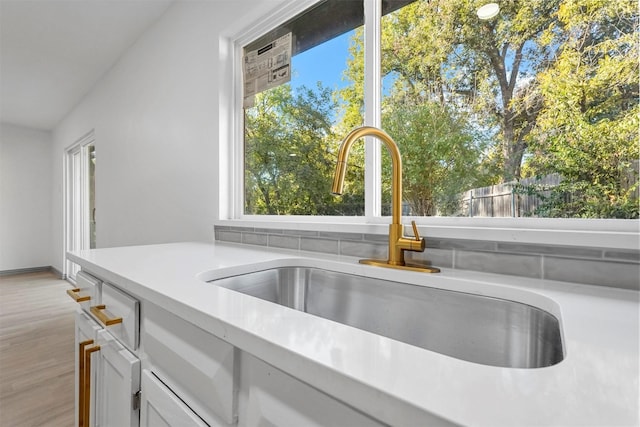 room details with sink, light wood-type flooring, and white cabinetry