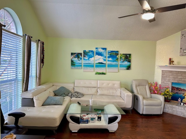 living room with ceiling fan, dark wood-type flooring, a textured ceiling, vaulted ceiling, and a fireplace