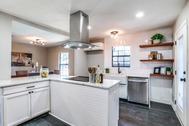 kitchen featuring kitchen peninsula, light stone counters, island range hood, dishwasher, and white cabinetry