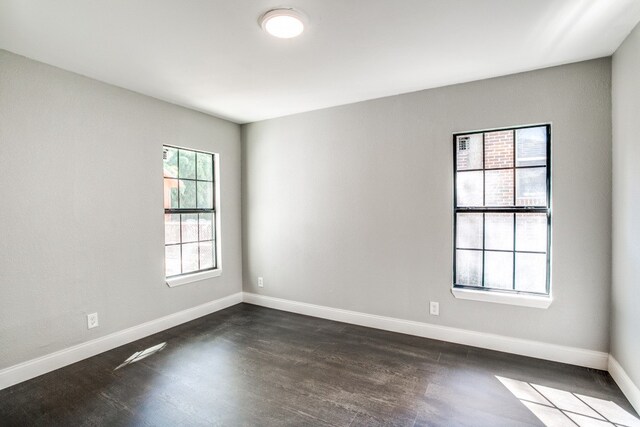 unfurnished room featuring a wealth of natural light and dark hardwood / wood-style floors