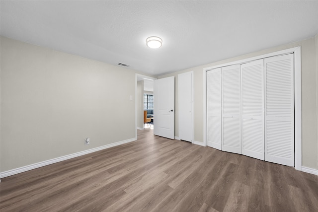 unfurnished bedroom with a closet, a textured ceiling, and hardwood / wood-style flooring