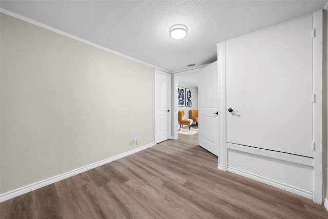 unfurnished bedroom with hardwood / wood-style flooring, crown molding, and a textured ceiling