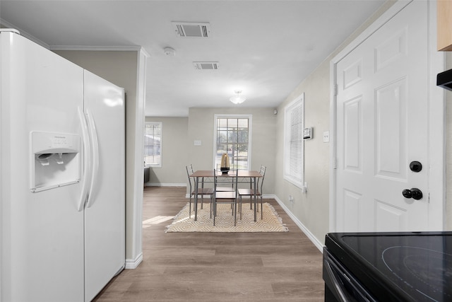 kitchen featuring light wood-type flooring, white refrigerator with ice dispenser, and ornamental molding