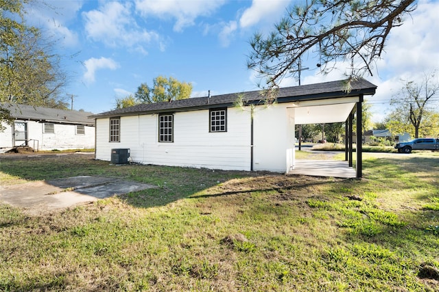 rear view of property with central AC, a yard, and a carport