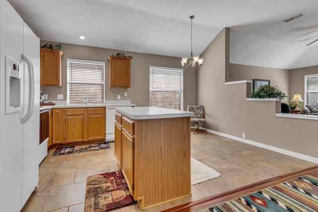 kitchen featuring plenty of natural light, a center island, white appliances, and decorative light fixtures