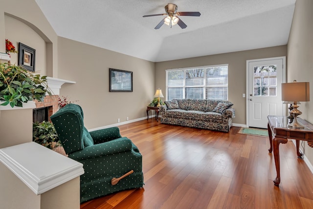 living room with hardwood / wood-style flooring, ceiling fan, lofted ceiling, and a textured ceiling