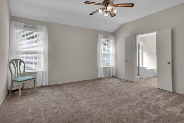 carpeted empty room featuring a wealth of natural light, ceiling fan, and vaulted ceiling