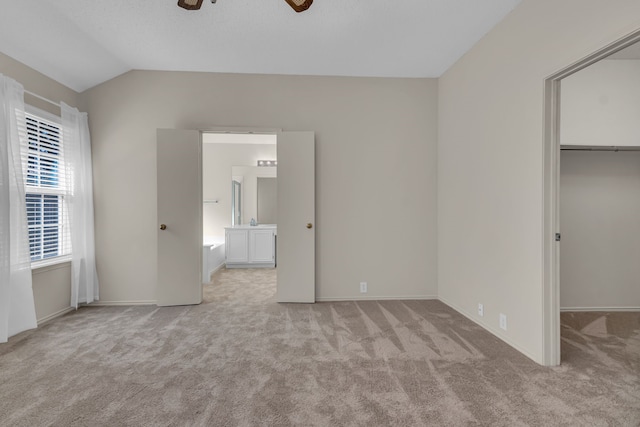 unfurnished bedroom with lofted ceiling, light carpet, a walk in closet, ceiling fan, and a closet