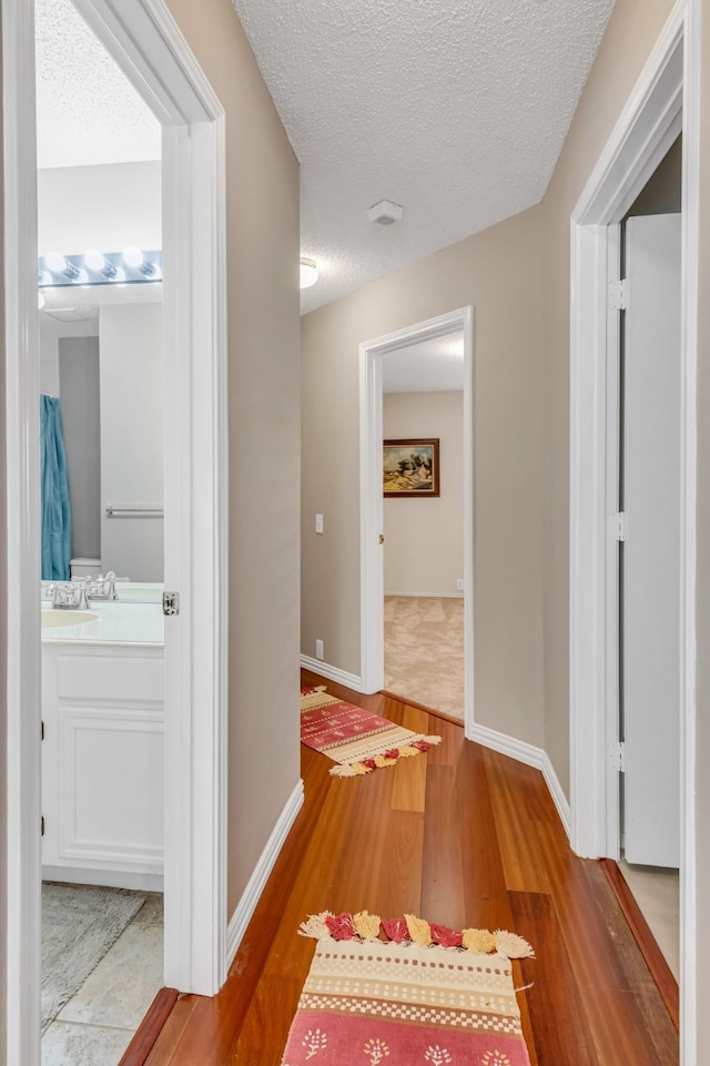 corridor with hardwood / wood-style floors and a textured ceiling