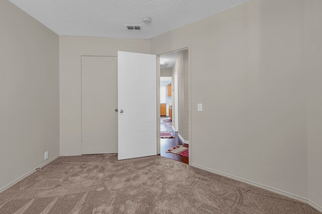 unfurnished bedroom featuring light colored carpet and a textured ceiling