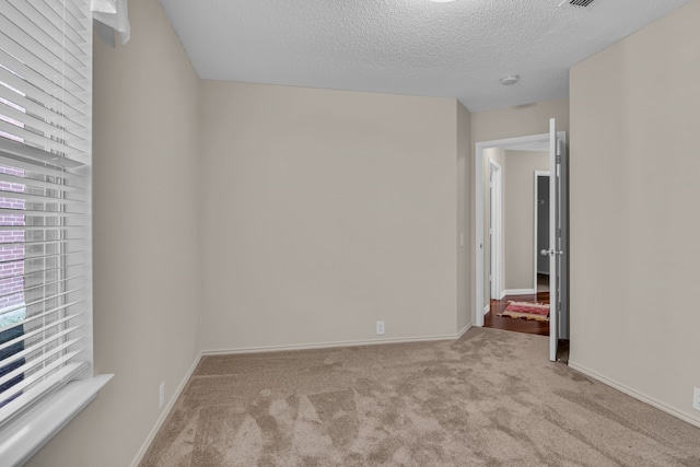 spare room with light colored carpet and a textured ceiling