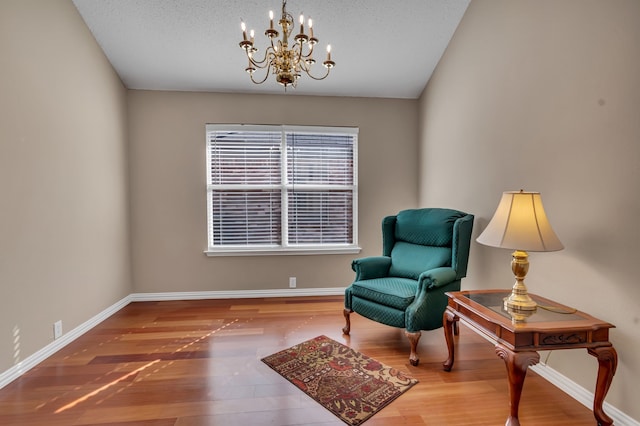 sitting room featuring a chandelier, wood-type flooring, and a textured ceiling