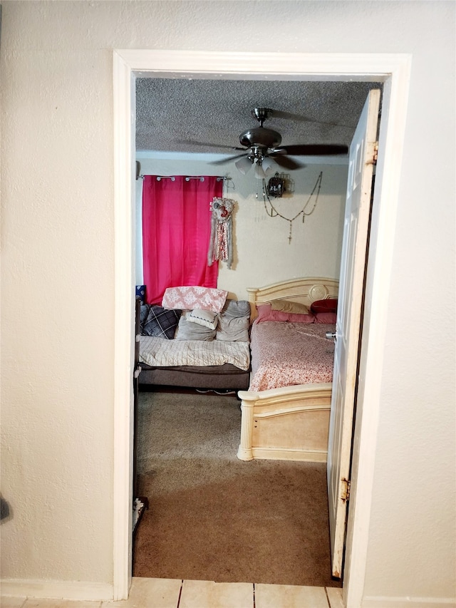 tiled bedroom with ceiling fan and a textured ceiling