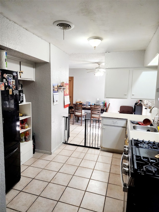 kitchen with ceiling fan, black appliances, sink, light tile patterned floors, and white cabinetry