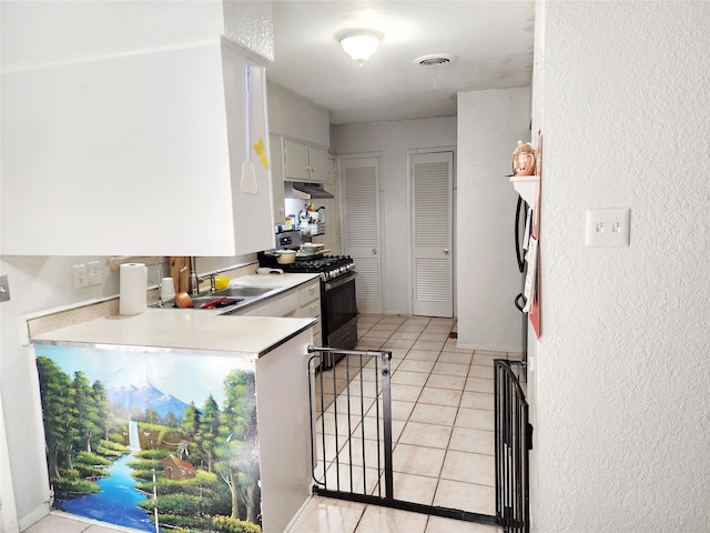 kitchen featuring light tile patterned floors, gas stove, white cabinetry, and sink