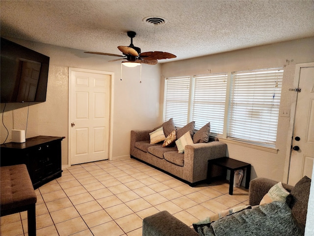 living room featuring ceiling fan, light tile patterned flooring, and a textured ceiling