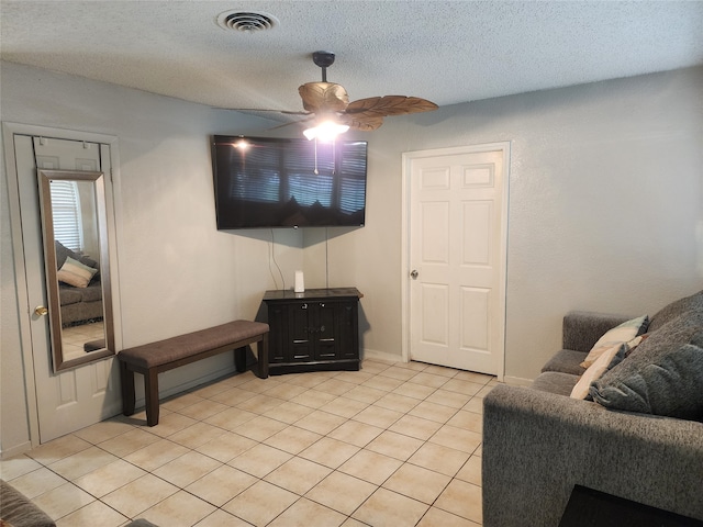 living room with ceiling fan, light tile patterned floors, and a textured ceiling