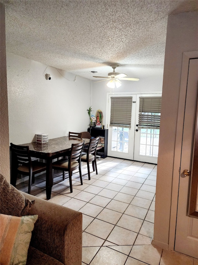 tiled dining space with ceiling fan, a textured ceiling, and french doors