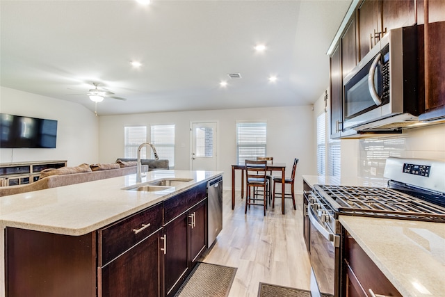 kitchen featuring ceiling fan, sink, light hardwood / wood-style floors, a kitchen island with sink, and appliances with stainless steel finishes