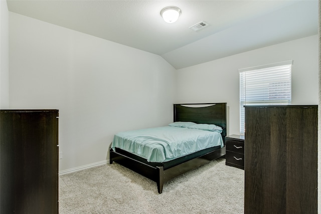 bedroom featuring light carpet and vaulted ceiling