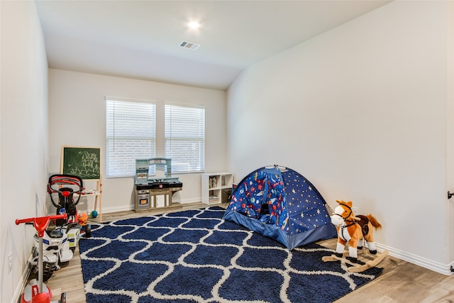 recreation room featuring wood-type flooring and vaulted ceiling