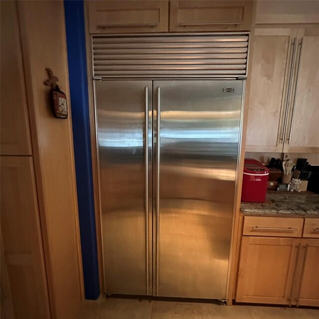 kitchen featuring stainless steel built in fridge and stone counters