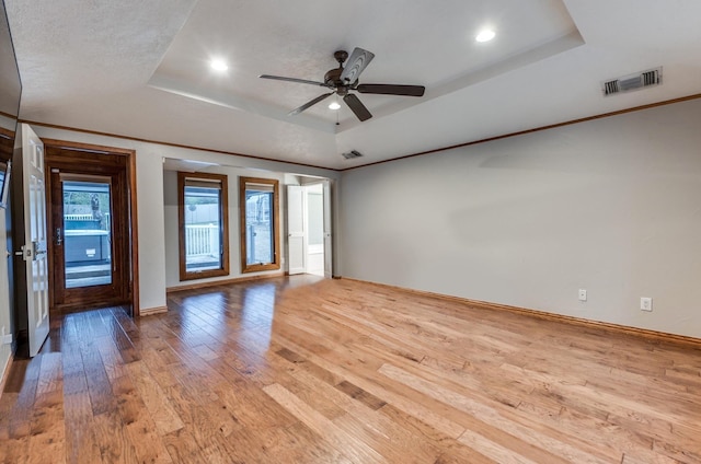 spare room with ceiling fan, light hardwood / wood-style floors, a raised ceiling, and a textured ceiling