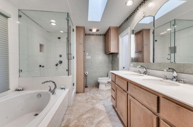 full bathroom featuring a skylight, separate shower and tub, toilet, vanity, and tile walls