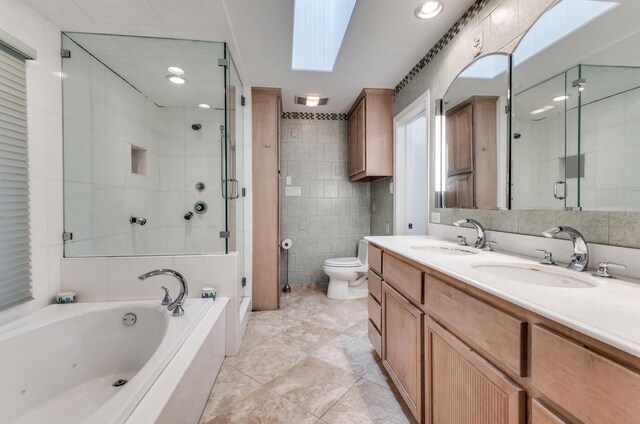 full bathroom featuring a skylight, separate shower and tub, toilet, vanity, and tile walls