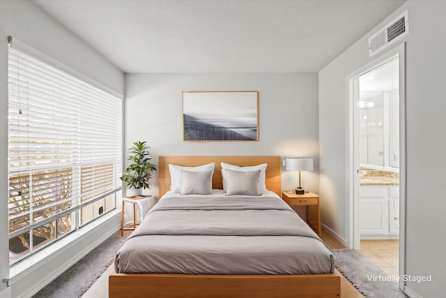 bedroom with light tile patterned floors and ensuite bath