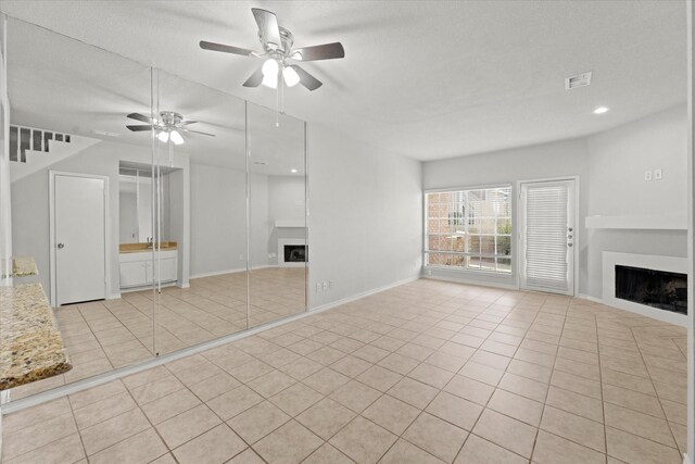 unfurnished living room with ceiling fan, light tile patterned flooring, and a textured ceiling