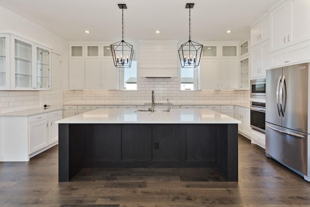 kitchen with sink, appliances with stainless steel finishes, dark hardwood / wood-style floors, white cabinets, and a center island with sink