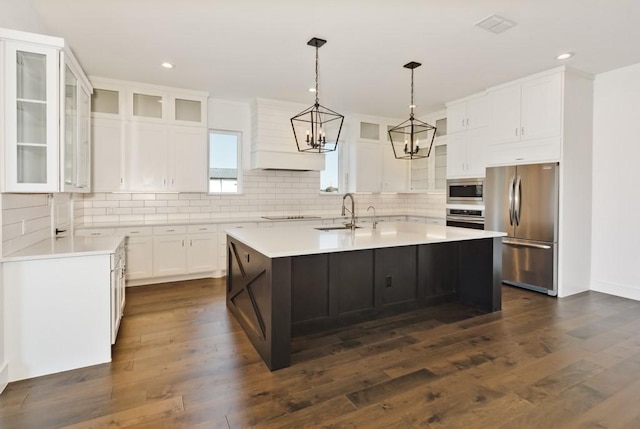 kitchen with sink, white cabinetry, stainless steel appliances, an island with sink, and dark hardwood / wood-style flooring