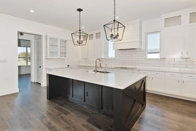 kitchen with black electric stovetop, sink, white cabinets, and a center island with sink