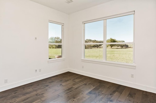 spare room featuring a healthy amount of sunlight and dark hardwood / wood-style flooring