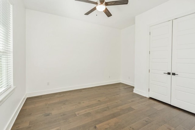 unfurnished bedroom featuring dark hardwood / wood-style flooring, ceiling fan, and a closet