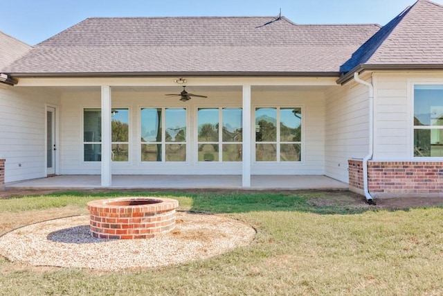 back of house featuring ceiling fan, a patio, a yard, and a fire pit