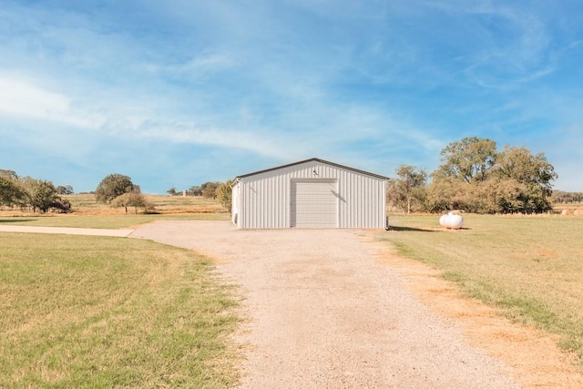 view of outbuilding featuring a garage, a lawn, and a rural view