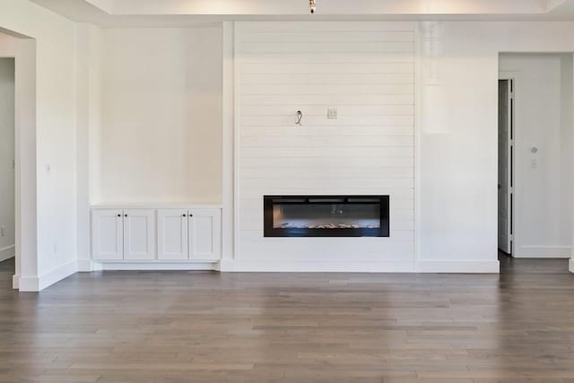 unfurnished living room featuring hardwood / wood-style flooring, a fireplace, and a tray ceiling