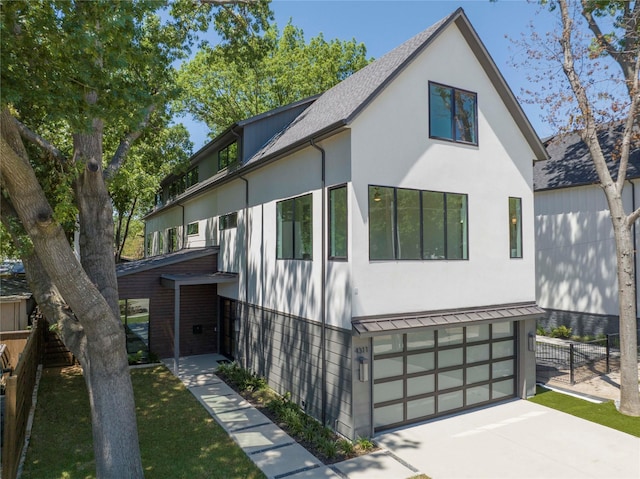 view of front of home featuring driveway, an attached garage, fence, and stucco siding