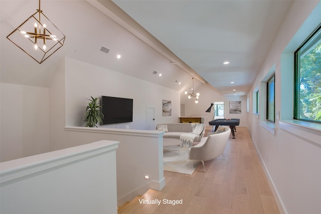 living room with a notable chandelier, plenty of natural light, light hardwood / wood-style floors, and vaulted ceiling with beams