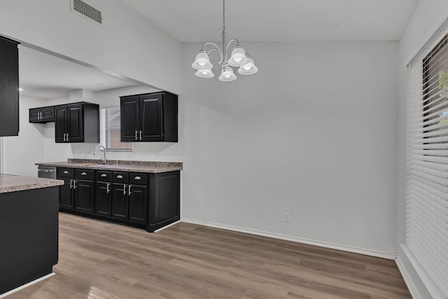 kitchen with a chandelier, sink, pendant lighting, and light wood-type flooring