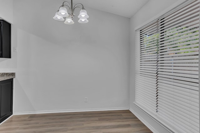 unfurnished dining area with hardwood / wood-style floors and an inviting chandelier