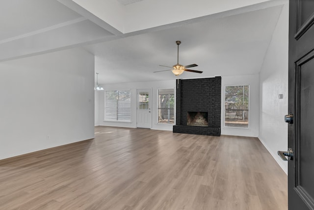 unfurnished living room featuring a fireplace, lofted ceiling, light hardwood / wood-style floors, and a healthy amount of sunlight