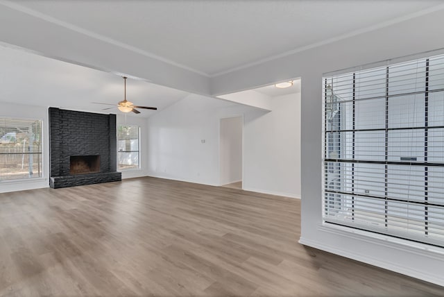 unfurnished living room with a large fireplace, ceiling fan, plenty of natural light, and wood-type flooring