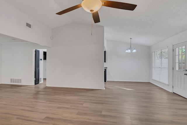 unfurnished room with ceiling fan with notable chandelier, lofted ceiling, a textured ceiling, and light hardwood / wood-style flooring