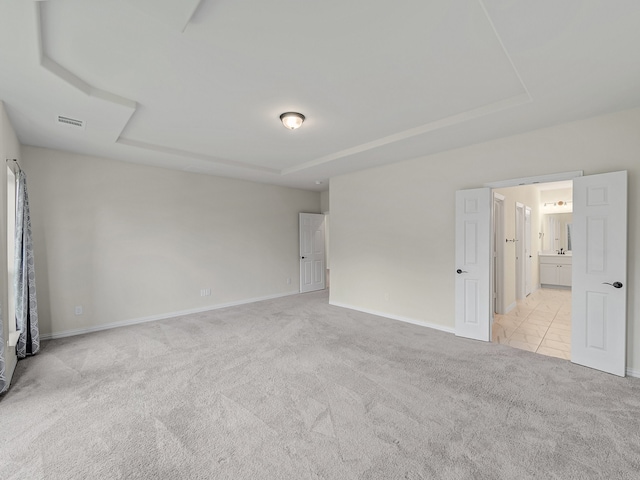 unfurnished bedroom with ensuite bathroom and light colored carpet