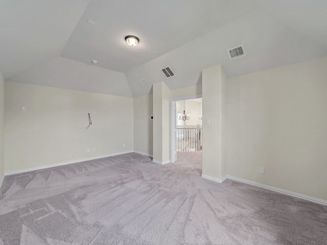 carpeted spare room with a notable chandelier and lofted ceiling