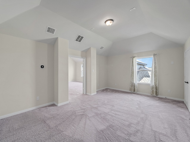 additional living space featuring light colored carpet and lofted ceiling