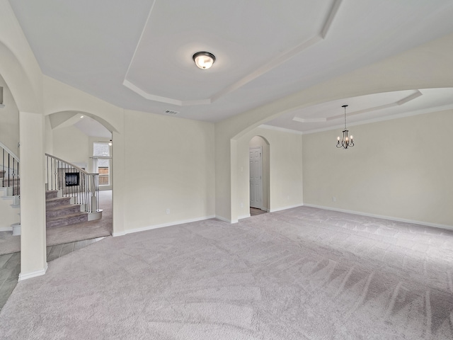 carpeted empty room featuring a chandelier, a tray ceiling, and ornamental molding